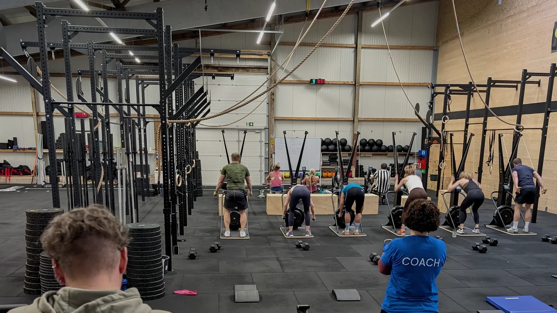 Laufende Class bei AMITY Athletics in Dülmen — mehrere Personen an BikeErgs, Coach im Vordergrund